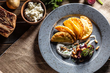 Baked homemade potato pies, creamy garlic dip, baked beetroot and roasted bacon - Top of view.の写真素材