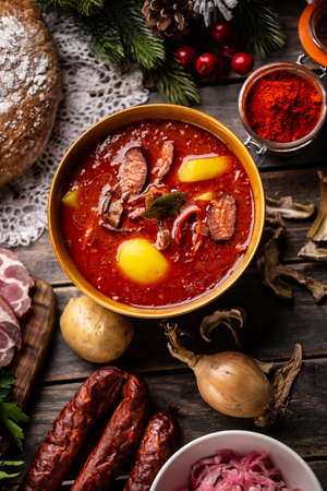 Top of view at cabbage soup - Kapustnica and ingredients for its preparation: Sauerkraut, sausage, smoked neck and knee, potatoes, onions, dried mushrooms, coriander and ground red pepper.の写真素材