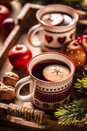 Two cups with Christmas hot punch cooked from red wine, rum and fresh fruit, flavored with cloves and cinnamon.の写真素材