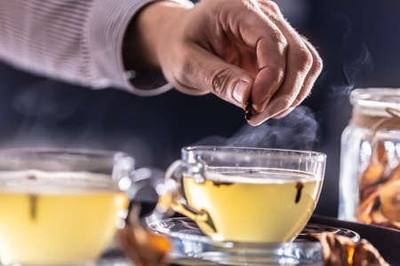 Detail of a bartender's hand flavoring hot mulled wine with cloves.