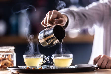 The bartender pours hot mulled wine or a winter whiskey drink Hot Teddy.の写真素材