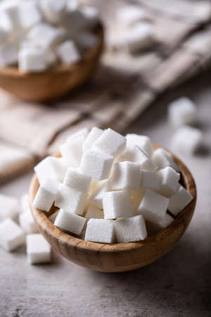 White sugar cubes in a wooden bowl on the table.の写真素材