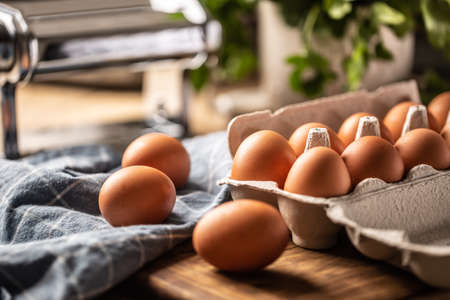 Fresh eggs in a cardboard box on a wooden board in the kitchen.