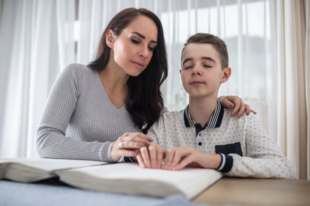 Woman helps blind boy to read a book in braille.の写真素材
