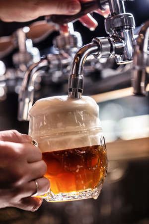 Mixing dark beer with light in one mug by tapping it from a tap, creating rich foam.の写真素材