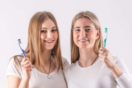 Two cute teenagers with a dental braces, they have toothbrushes in their hands.の写真素材