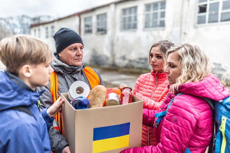 Male NGO worker gives a box of basic food and toiletries to a family of three at the border fleeing the conflict in Ukraine.の写真素材