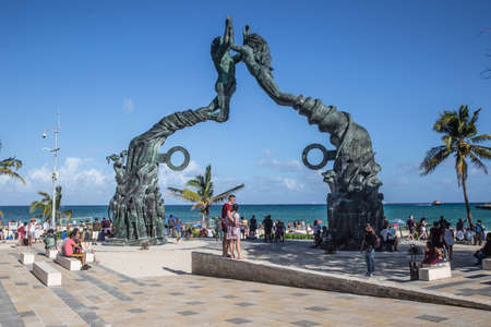 Portal Maya, Mexico. March 19. 2022: Portal Maya sculpture in Playa del Carmen in Quintana Roo in Mexico with plenty of tourists sitting around and a couple standing below it.のeditorial素材