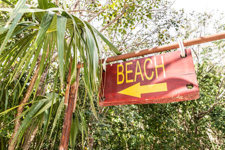 Sign saying Beach and an arrow pointing to the left directs tourists to the nearest seaside in tropical destination.の写真素材