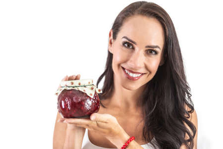 A rustic jar full of tasty jam held by and attractive brunette. Isolated background.