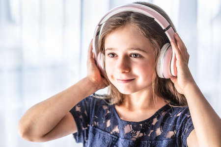 A small child listens to music through wireless headphones.