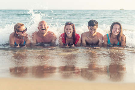 A cheerful family lies on the shore of the sea, enjoying the tide of the waves.