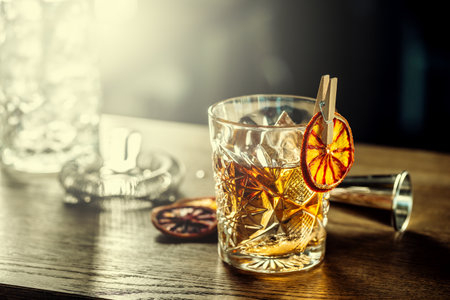 Old fashioned classic cocktail drink in crystal glass on bar counter.