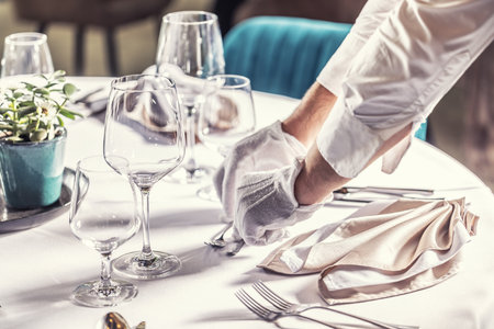 The waiter prepares the festive table in the hotel restaurant.の写真素材