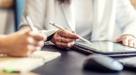The hands of two female colleagues are using a digital tablet and a notebook. A business meeting to discuss financial management, accounting or financial advice.の写真素材