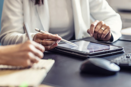 The hands of two female colleagues are using a digital tablet and a notebook. A business meeting to discuss financial management, accounting or financial advice.の写真素材