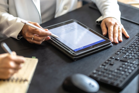 The hands of two female colleagues are using a digital tablet and a notebook. A business meeting to discuss financial management, accounting or financial advice.の写真素材