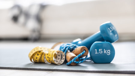 Jump rope and tape measure on the mat at home in the living room. Concept of healthy lifestyle.の写真素材