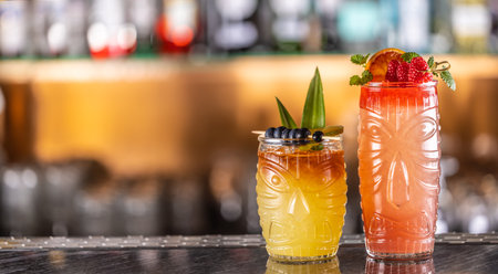 Mai tai cocktails in hawaiian glasses garnished with pineapple, blueberries and strawberries on bar counter.の写真素材