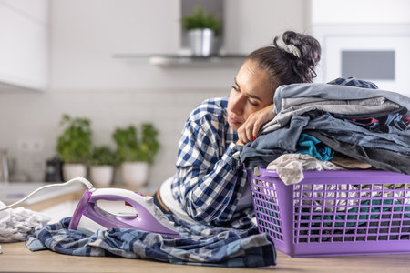 Wife fell asleep on a pile of clothes in the basket keeping the iron on next to her.の写真素材