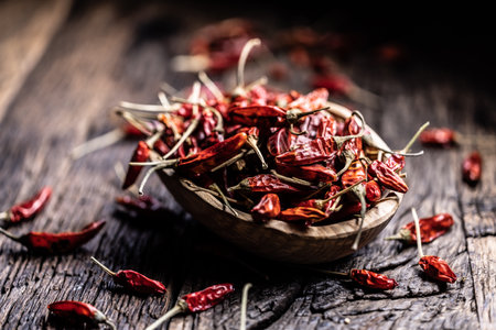Dried chili peppers in a woodem bowl on a rustic table.の写真素材