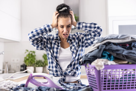 Housewife has shocked expression and mouth open over neverending chores and basket full of unironed clothes.の写真素材