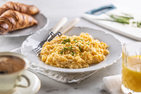 Breakfast served with a plate of scrambled eggs, croissants, orange juice and cofffee.の写真素材