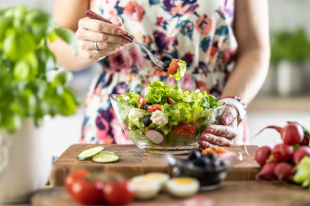 A portion of healthy salad on a fork in the hand of a young woman.の写真素材