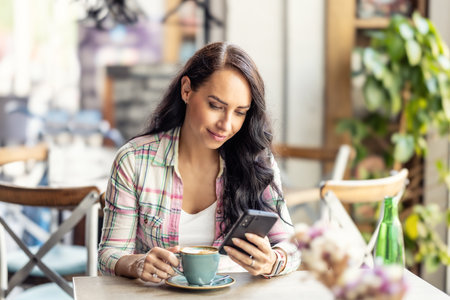 Portrait of beautiful woman using her smarphone in cafe, he reads received messages and follows social networks.の写真素材