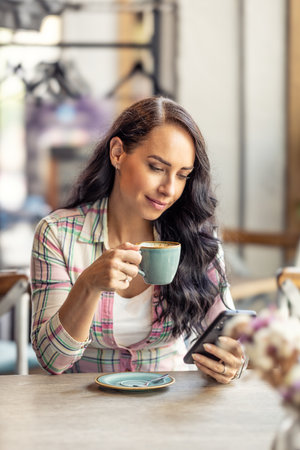 Portrait of beautiful woman using her smarphone in cafe, he reads received messages and follows social networks.の写真素材