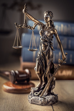Statute of Justice and law books in the background.の写真素材