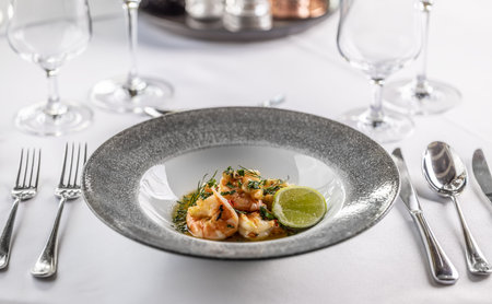 Grilled shrimps with chilli and garlic in a design plate on a set table.の写真素材