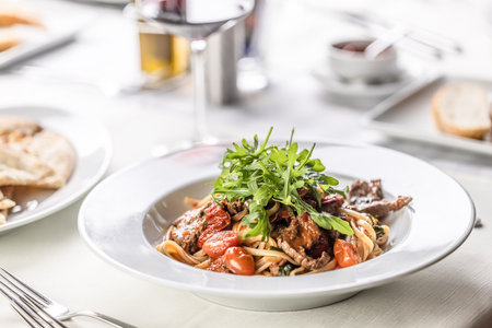 Italian coooking of linguine with meat, tomatoes and ruccola on top.の写真素材