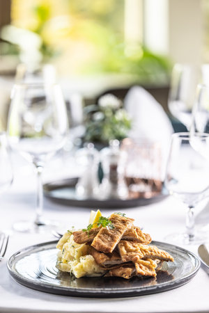Viennese schnitzel cut into strips and styled on a potato salad in the restaurant.の写真素材
