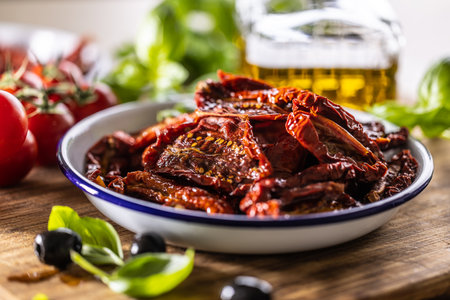 Sun-dried tomatoes marinated in olive oil with herbs and olives.の写真素材