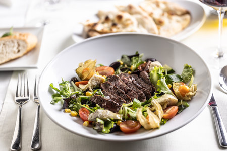 Colorful mixed salad with steak slices placed on top of it.の写真素材