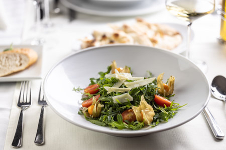 Table set for a lunch or dinner with rocket salad with tomatoes, physalis and parmesan.の写真素材