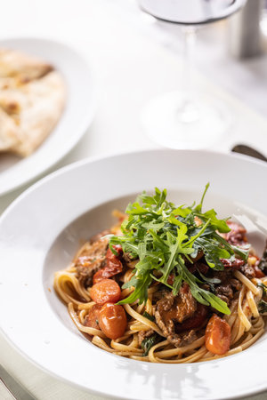 Tomato linguine with meat and ruccola served in a fancy plate.の写真素材