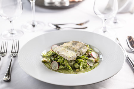 Restaurant serves cog fillet with green salad leaves and raddish in a deep plate.の写真素材