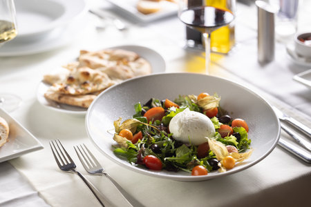 Italian salad with ball of Buffalo mozzarella in the middle served in a plate with a flatebread and red wine.の写真素材