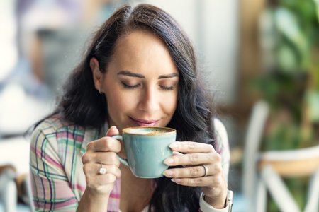 A brunette enjoys the smell of freshly brewed coffee in a cafe.の写真素材