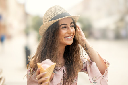 Portrait of a beautiful smiling lady in a summer outfit holding an ice cream on a hot summer day.の写真素材