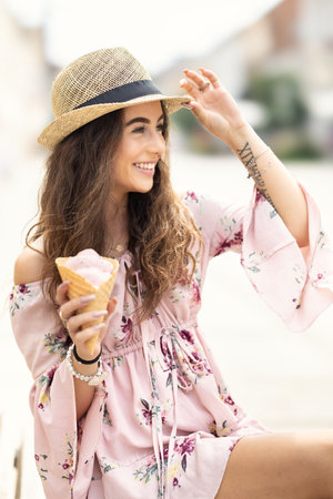 Portrait of a beautiful smiling lady in a summer outfit holding an ice cream on a hot summer day.の写真素材