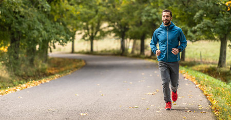 A young man is training and running in an autumn park.