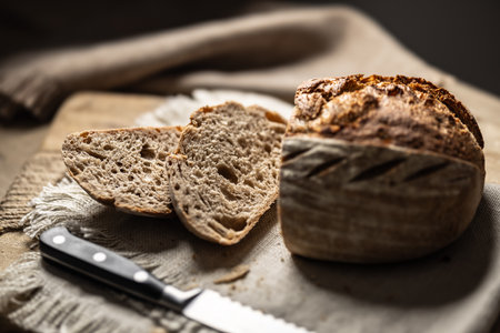 Fresh sourdough bread with a cut slice on a cutting board..