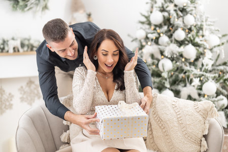 Excited woman finds out her man put a Christmas present in front of her.の写真素材