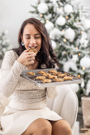 Woman enjoys the tastes of freshly baked Christmas cookies straight from the tray.の写真素材