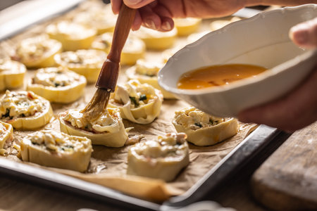 The cook brushes an egg onto a puff pastry roll. Recipe procedure: 9 of 10