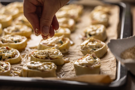 Female cooks hands sprinkle sesame on raw mini cakes before baking. Recipe procedure: 10 of 10の写真素材