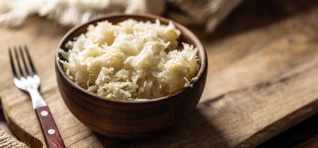 Fermented cabbage in a bowl on wooden cutting board.の写真素材